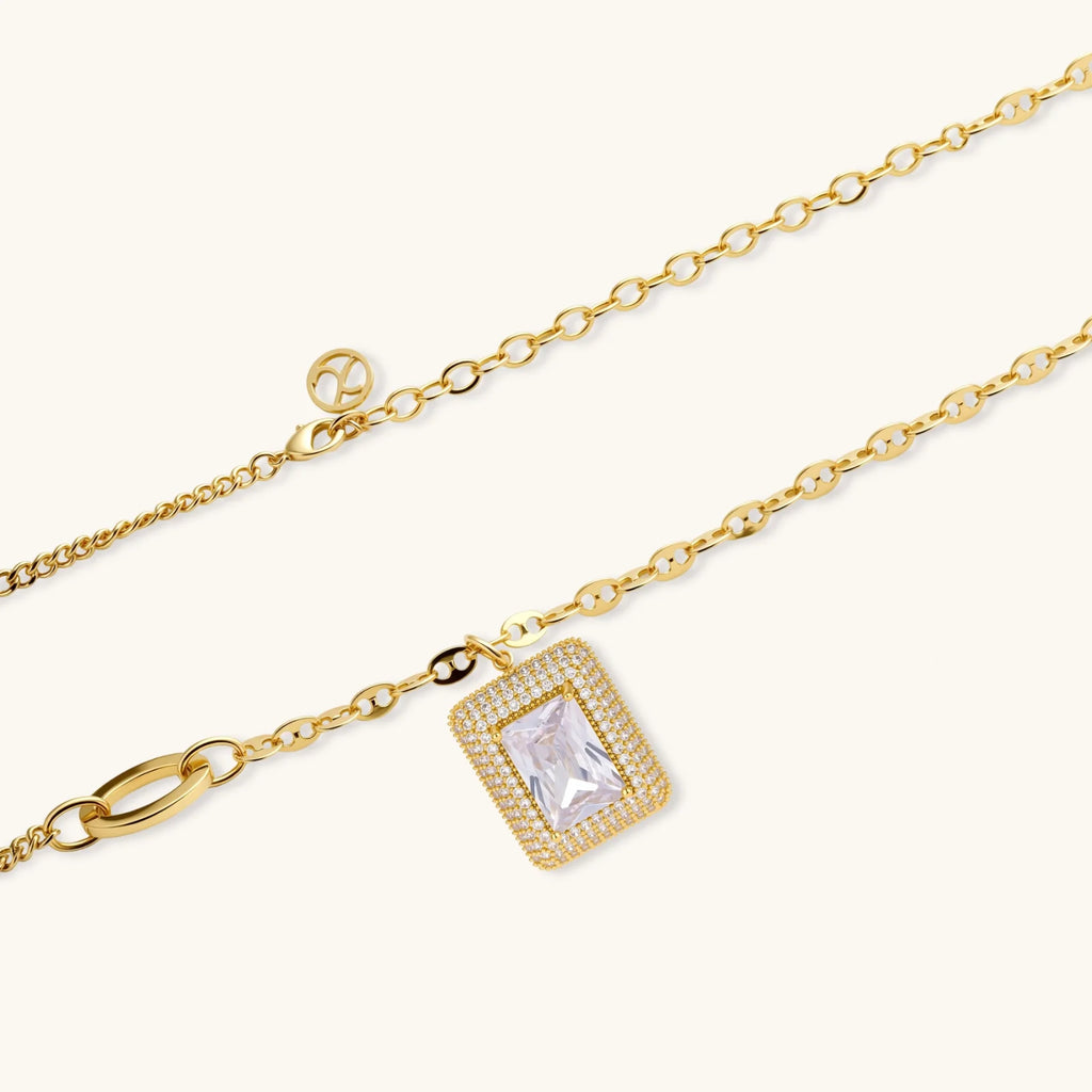 Gold-plated jewelry set with rectangular cubic zirconia stones in pave halo settings on cream background