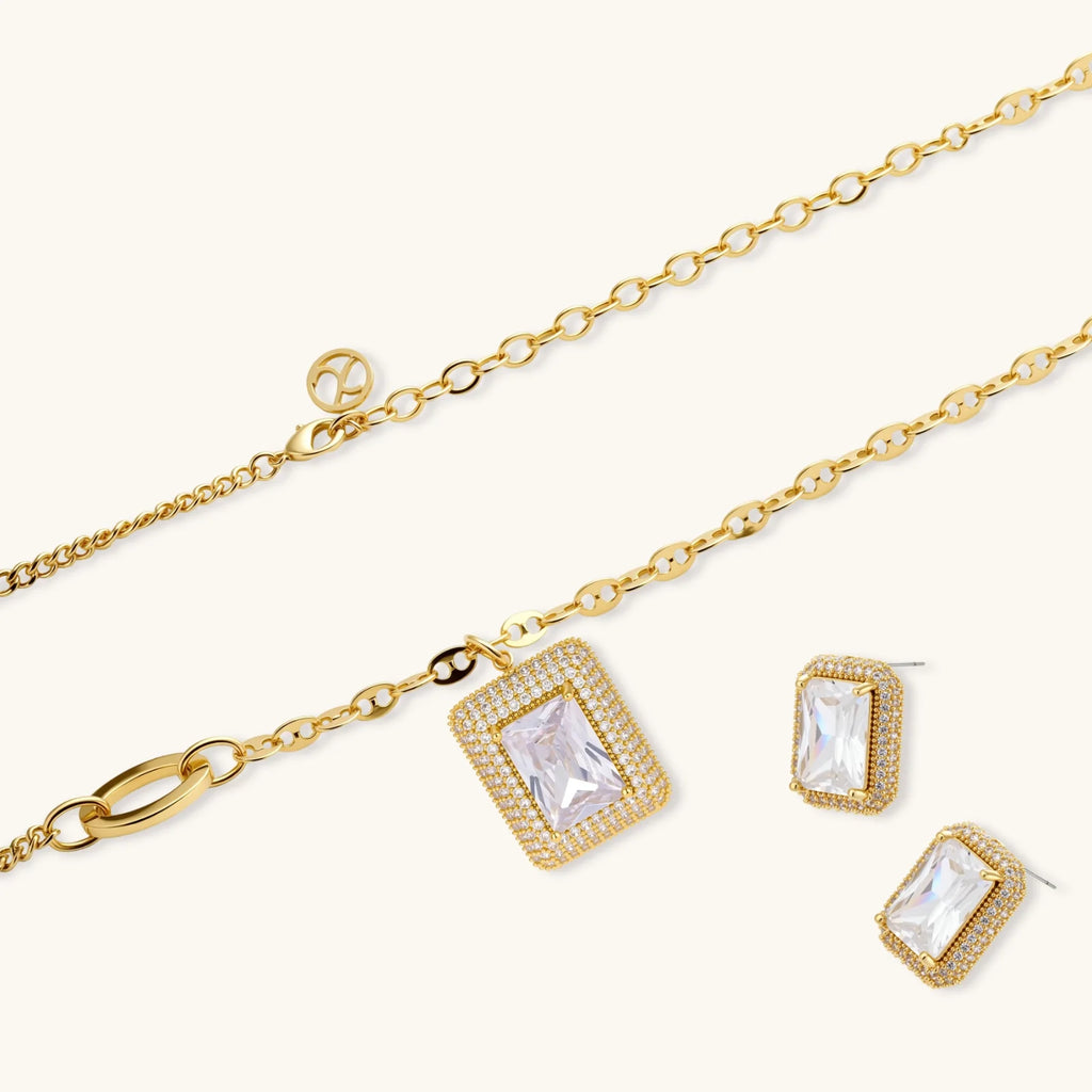 Gold-plated jewelry set with rectangular cubic zirconia stones in pave halo settings on cream background